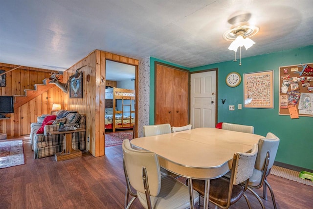 dining room featuring wood walls, ceiling fan, and dark hardwood / wood-style floors