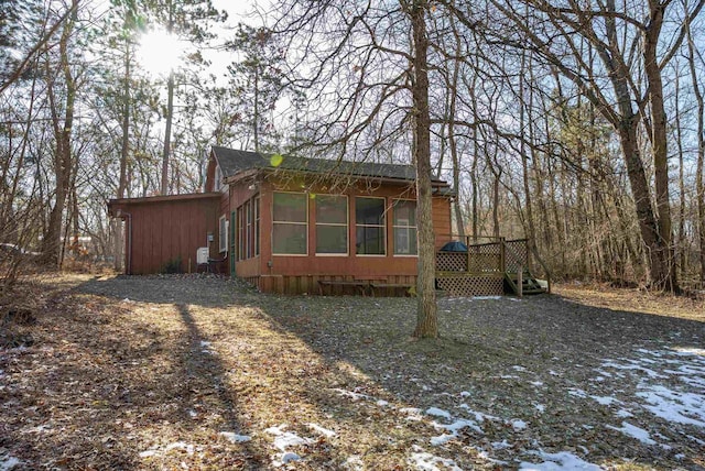 snow covered property with a deck and a sunroom