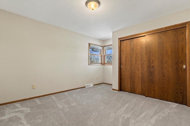 unfurnished bedroom with light colored carpet and a closet