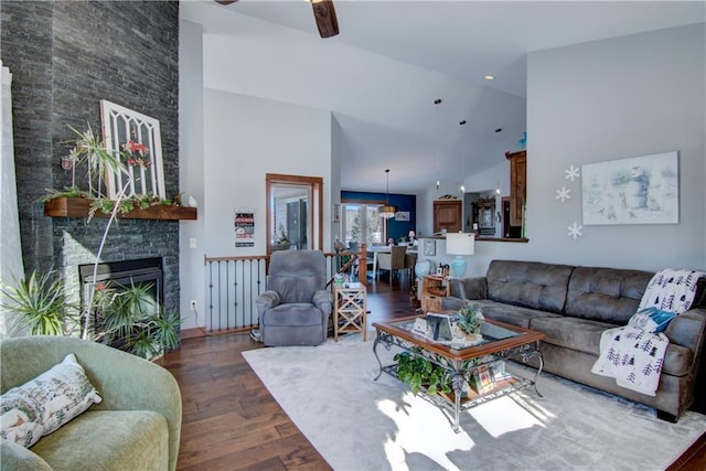 living room featuring high vaulted ceiling, a fireplace, ceiling fan, and dark hardwood / wood-style floors