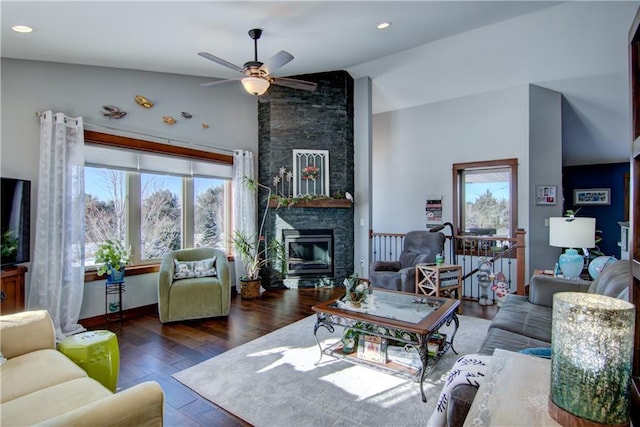 living room featuring lofted ceiling, dark hardwood / wood-style floors, a healthy amount of sunlight, and a stone fireplace