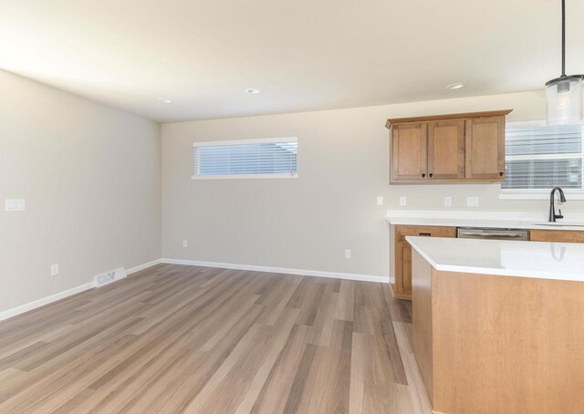 kitchen featuring sink, decorative light fixtures, light hardwood / wood-style flooring, and stainless steel dishwasher