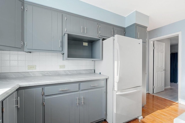 kitchen with light wood-type flooring, white fridge, and gray cabinets