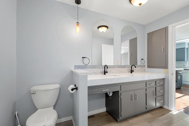 bathroom featuring toilet, backsplash, and vanity