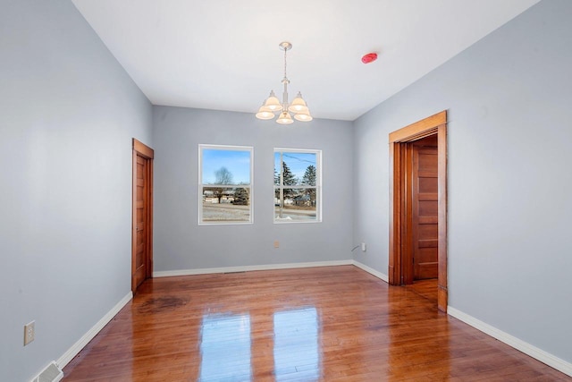 empty room featuring a chandelier and hardwood / wood-style flooring