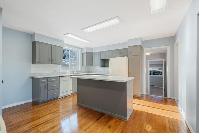 kitchen with white appliances, light hardwood / wood-style floors, decorative backsplash, a kitchen island, and gray cabinetry