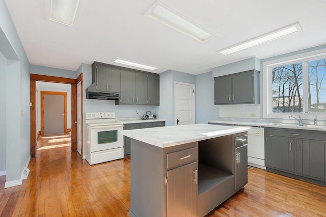 kitchen with sink, white appliances, light hardwood / wood-style flooring, gray cabinets, and a kitchen island