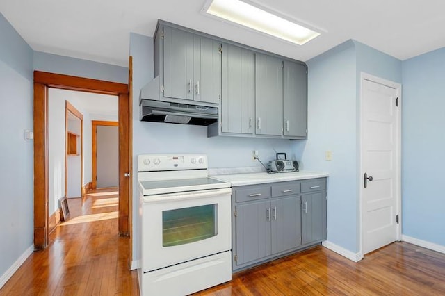 kitchen with light hardwood / wood-style flooring, gray cabinets, and white range with electric stovetop