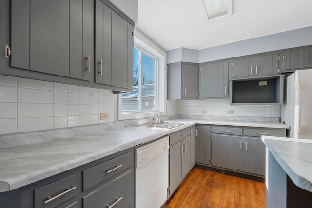 kitchen featuring white appliances, light hardwood / wood-style flooring, gray cabinets, and tasteful backsplash