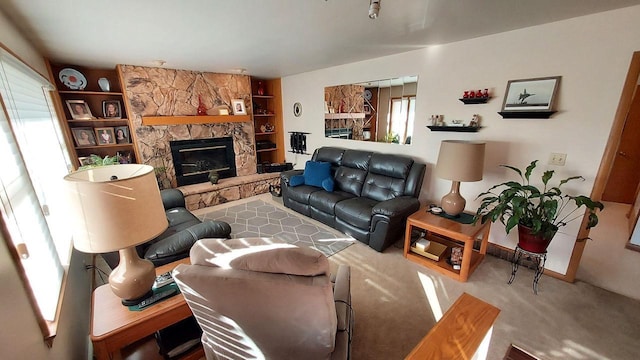 living room with a stone fireplace, built in features, and carpet floors