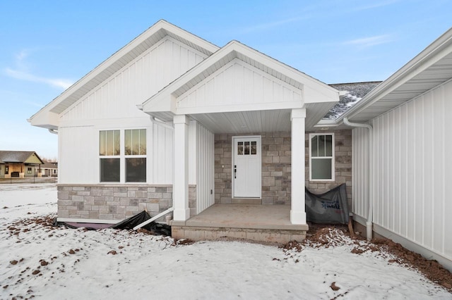 snow covered property entrance with covered porch