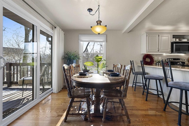 dining space featuring beam ceiling, a healthy amount of sunlight, and dark hardwood / wood-style floors