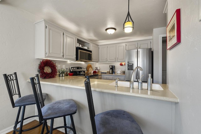 kitchen featuring pendant lighting, hardwood / wood-style floors, a kitchen bar, stainless steel appliances, and kitchen peninsula