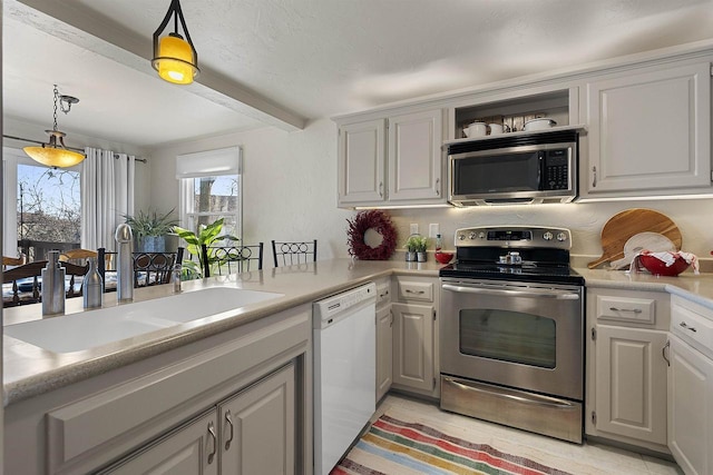 kitchen featuring decorative light fixtures, stainless steel appliances, beamed ceiling, sink, and kitchen peninsula