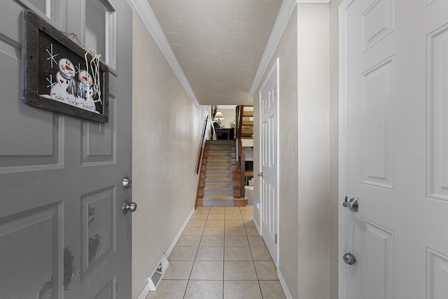 hallway featuring light tile patterned floors, crown molding, and a textured ceiling