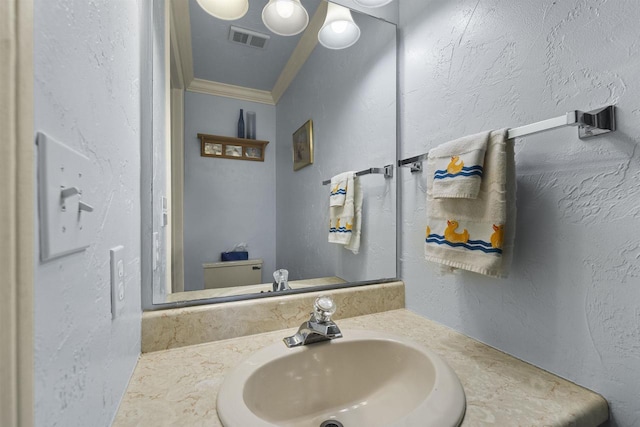 bathroom featuring toilet, crown molding, and vanity