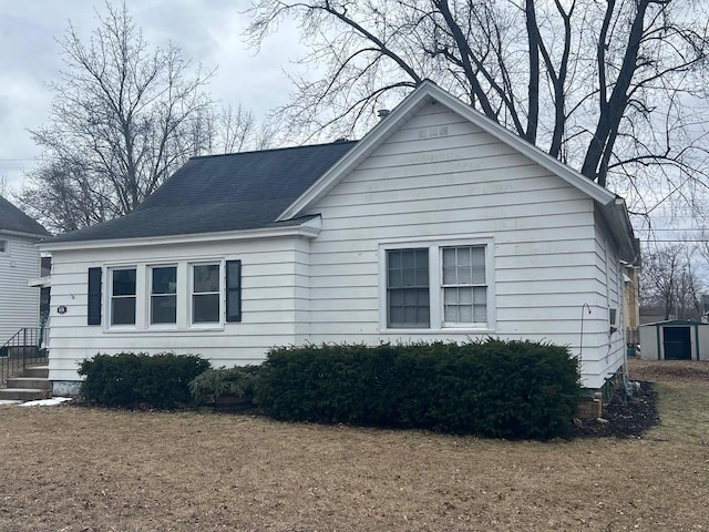 view of home's exterior with a storage unit and a lawn