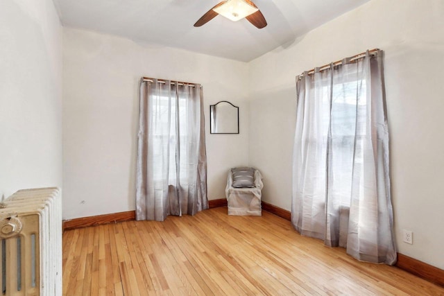 unfurnished room featuring a healthy amount of sunlight, radiator heating unit, and light wood-type flooring