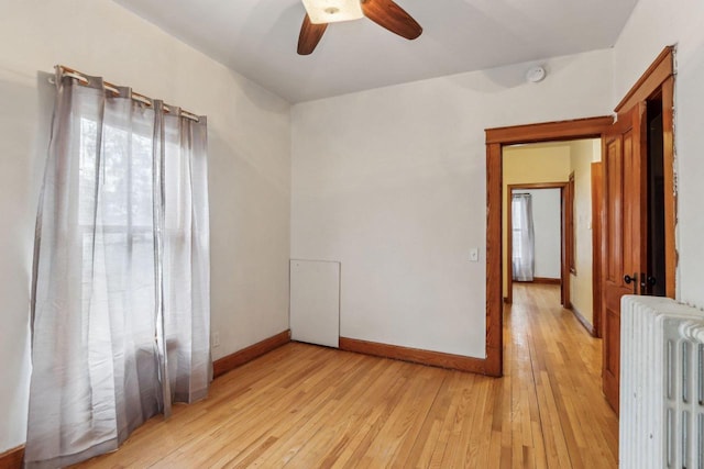 spare room with ceiling fan, radiator heating unit, and light hardwood / wood-style floors