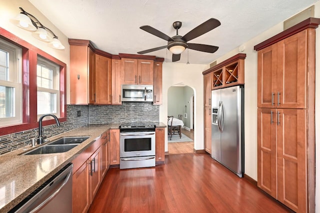 kitchen with sink, light stone counters, ceiling fan, tasteful backsplash, and appliances with stainless steel finishes