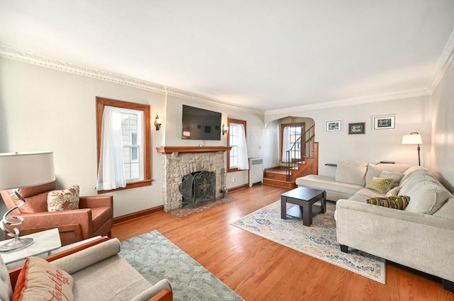 living room featuring radiator heating unit, ornamental molding, light wood-type flooring, and a fireplace