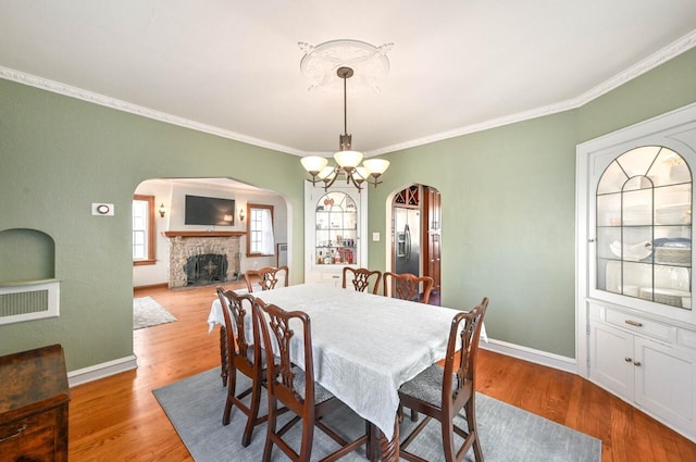 dining space featuring light hardwood / wood-style floors, a stone fireplace, and a wealth of natural light