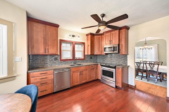 kitchen featuring sink, stainless steel appliances, ceiling fan with notable chandelier, and dark wood-type flooring