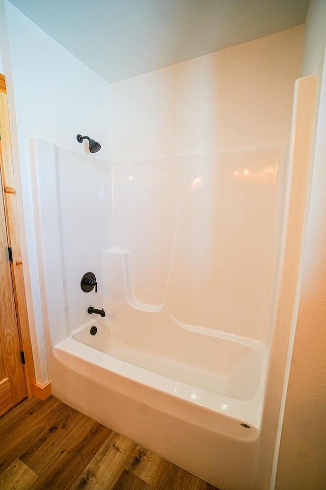 bathroom featuring hardwood / wood-style flooring and  shower combination