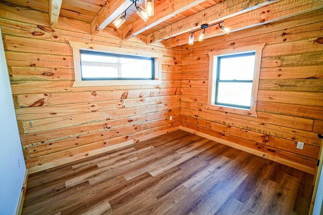 spare room with wooden ceiling, wood walls, beamed ceiling, and wood-type flooring