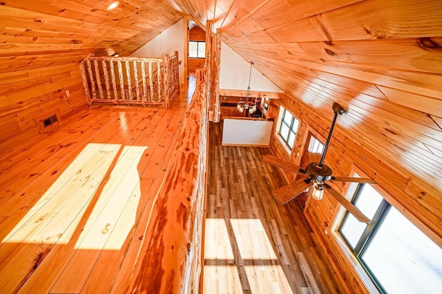 interior space with ceiling fan, wooden walls, vaulted ceiling, and hardwood / wood-style flooring