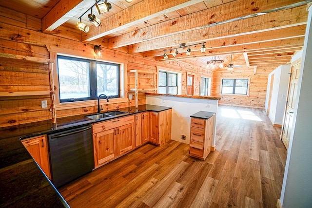 kitchen with wood walls, dishwasher, beam ceiling, and sink