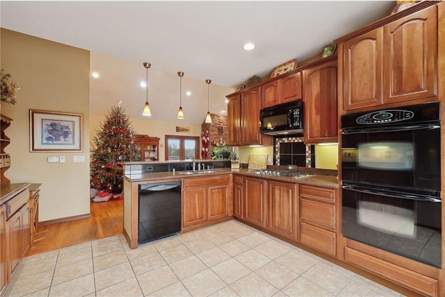 kitchen with sink, decorative light fixtures, light tile patterned floors, kitchen peninsula, and black appliances