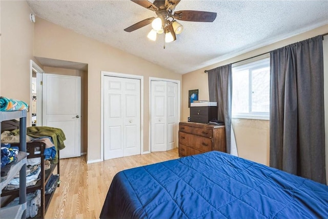 bedroom with ceiling fan, light hardwood / wood-style flooring, vaulted ceiling, and a textured ceiling