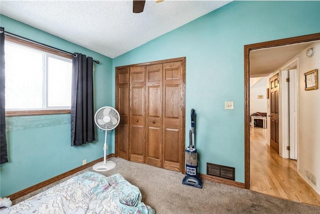 carpeted bedroom featuring lofted ceiling, a closet, ceiling fan, and a textured ceiling