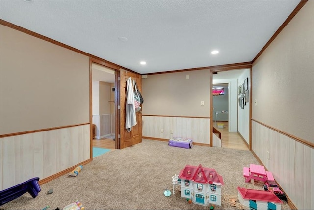 game room featuring a textured ceiling, light carpet, and crown molding