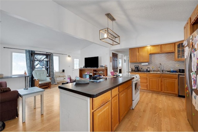 kitchen with lofted ceiling, light wood-type flooring, tasteful backsplash, hanging light fixtures, and appliances with stainless steel finishes