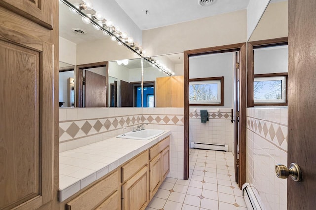 bathroom with tile walls, tile patterned flooring, vanity, and a baseboard heating unit