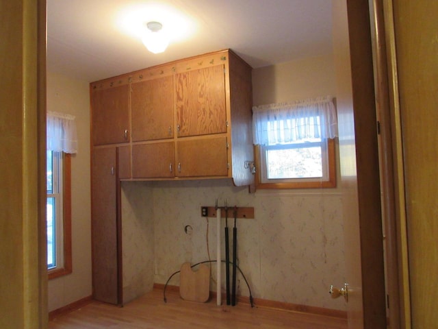 clothes washing area featuring laundry area, baseboards, and light wood finished floors