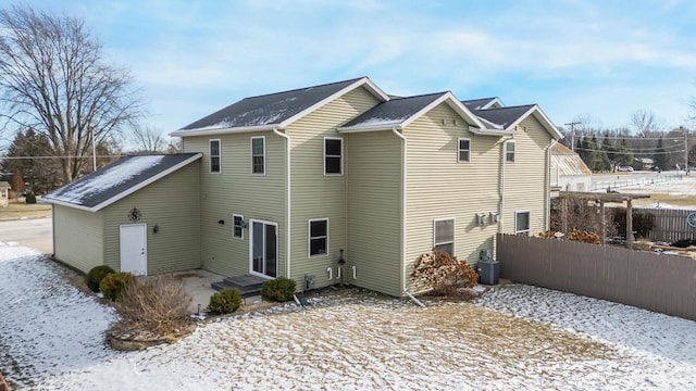 snow covered back of property with central AC