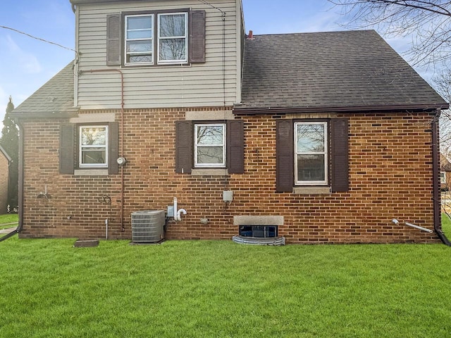 rear view of property featuring central AC and a lawn