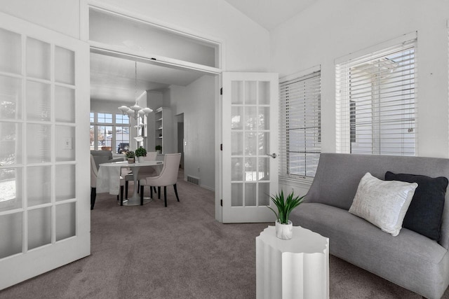 living room with lofted ceiling, french doors, carpet floors, and a notable chandelier