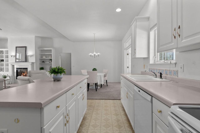 kitchen featuring sink, a tile fireplace, white cabinetry, dishwasher, and hanging light fixtures