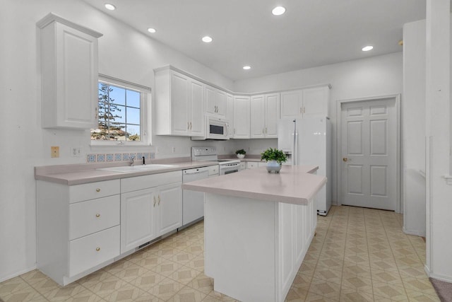 kitchen featuring white appliances, a center island, white cabinetry, and sink