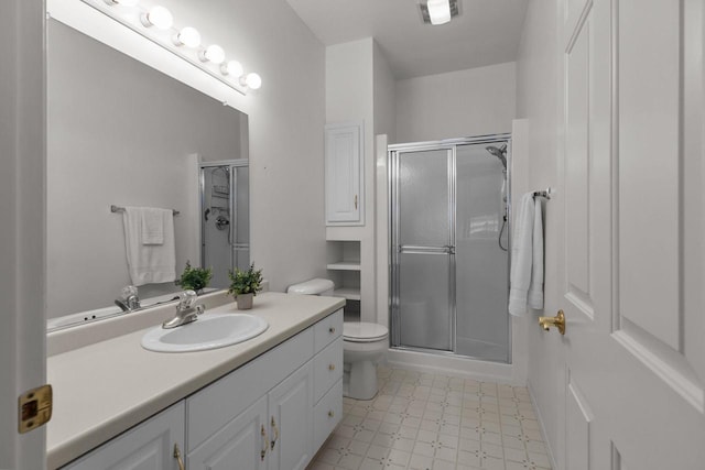 bathroom with a shower with door, vanity, and toilet