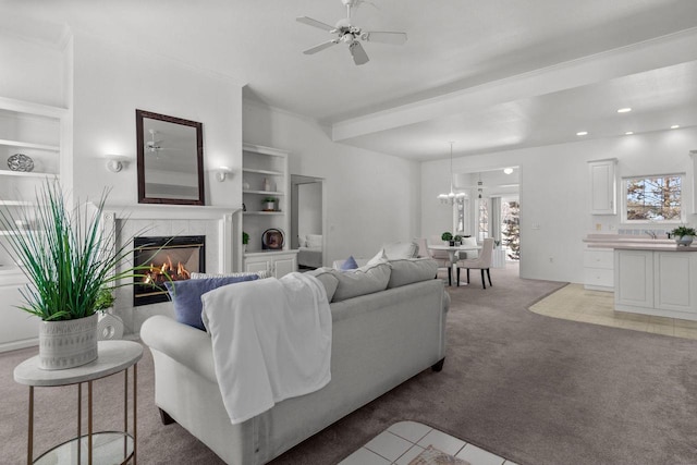 carpeted living room featuring a high end fireplace, sink, ceiling fan, and built in shelves