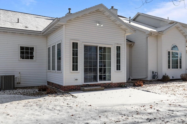 snow covered rear of property with central AC