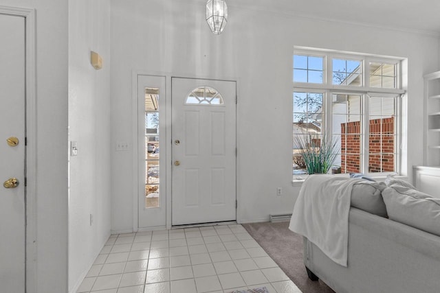 tiled entrance foyer with ornamental molding, a healthy amount of sunlight, and a notable chandelier