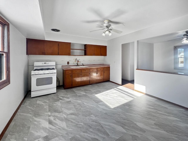 kitchen featuring sink, ceiling fan, white gas range oven, and decorative backsplash