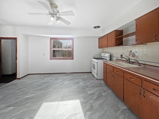 kitchen featuring ceiling fan, gas range gas stove, tasteful backsplash, and sink