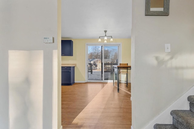 corridor with an inviting chandelier and light hardwood / wood-style flooring